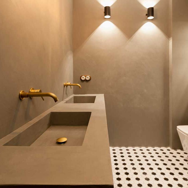 Modern bathroom with microcement sink, gold fixtures, and a toilet.
