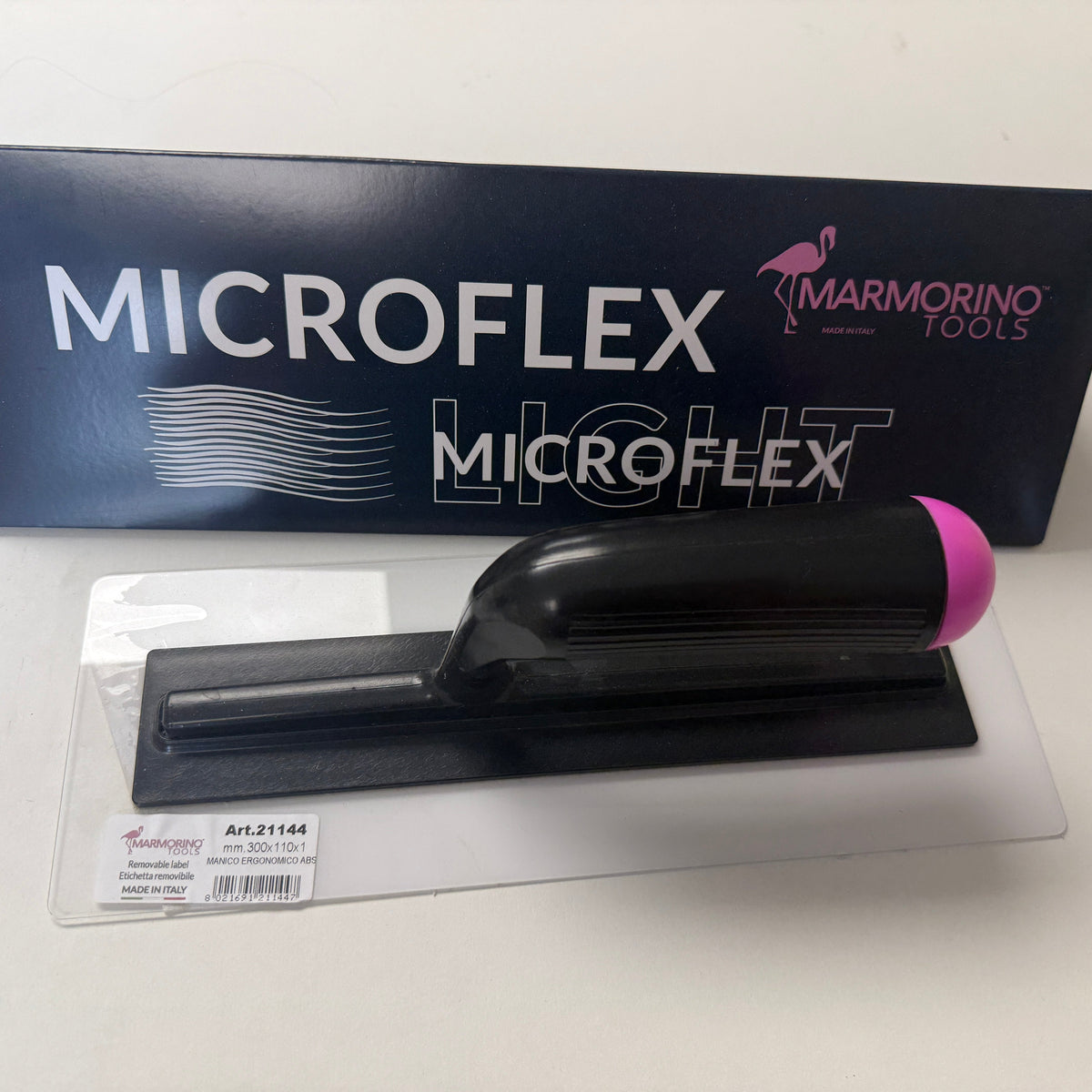 A black and pink Microflex trowel blade in its clear plastic packaging, next to its dark blue and white branded cardboard box.